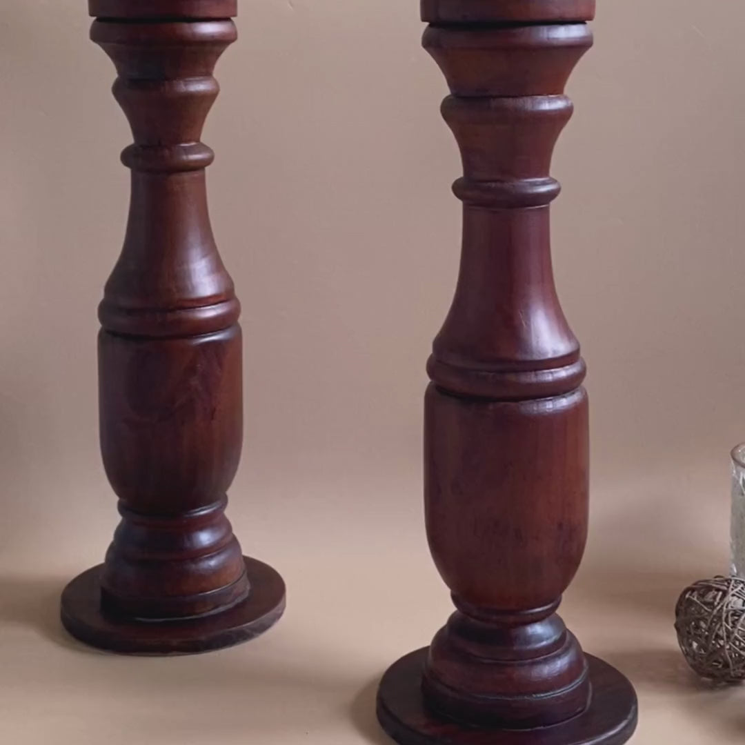 Another video of Two wooden hand carved flower vases with white flowers on top and an unlit candle with fur like balls on the side